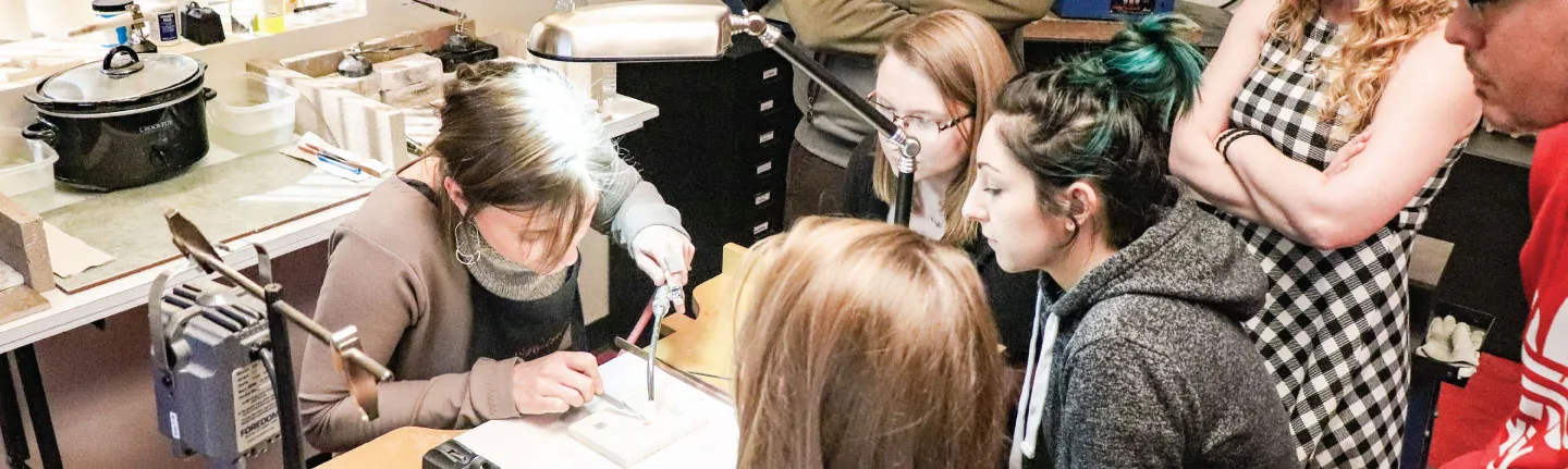 Jewelry students watching a teacher give a demo on jewelry making